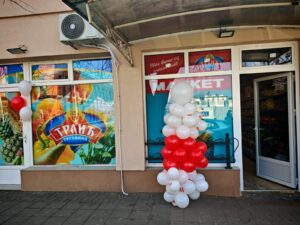 Ulaz u market Trlić sa balonima i staklenim izlogom u Obrenovcu. Povoljna kupovina. Loklacije prodavnica. Povoljna kupovina sa velikim popustima na proizvode u Trliću